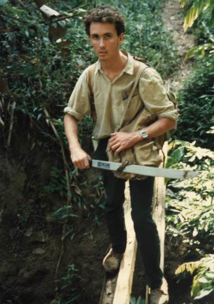 The author (Andrew Egan) crossing a log bridge
              on day one of the expedition with a newly-purchased
              machete